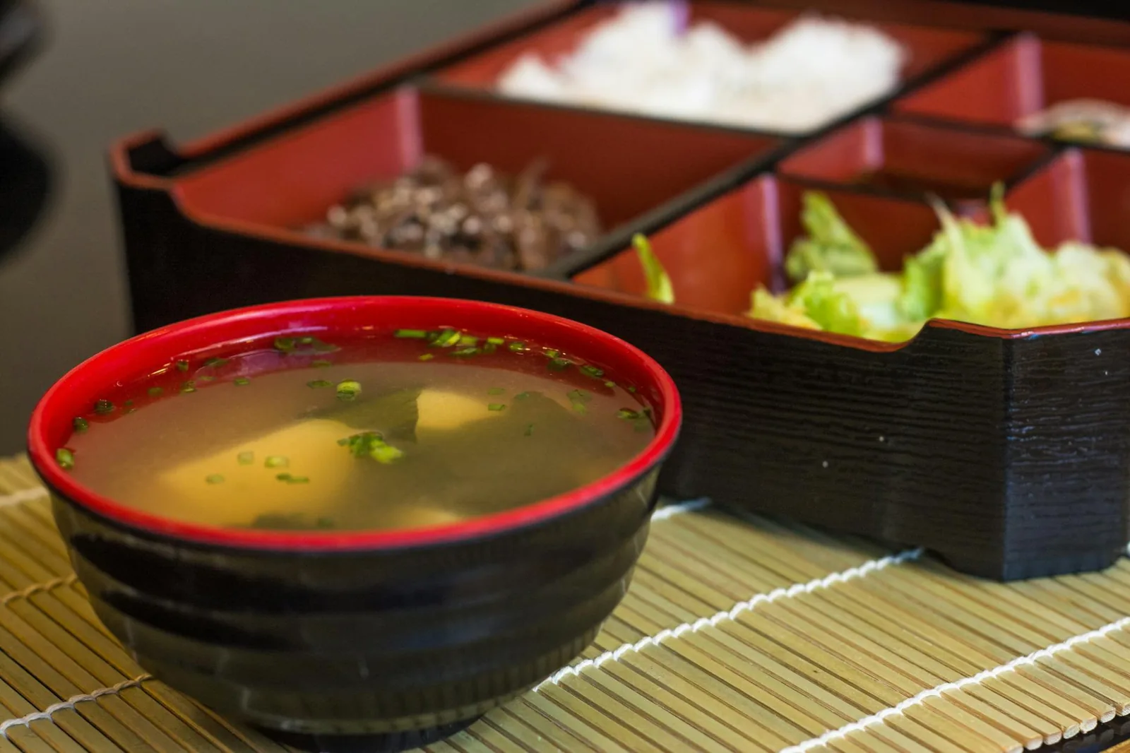Close-up of a traditional Japanese bento box featuring a bowl of miso soup and various side dishes.